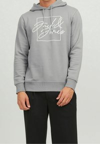 Sudadera con capucha gris hecha de una tela suave, que presenta un diseño gráfico blanco dentro de un cuadrado en la parte delantera, con puños y dobladillo acanalados.
