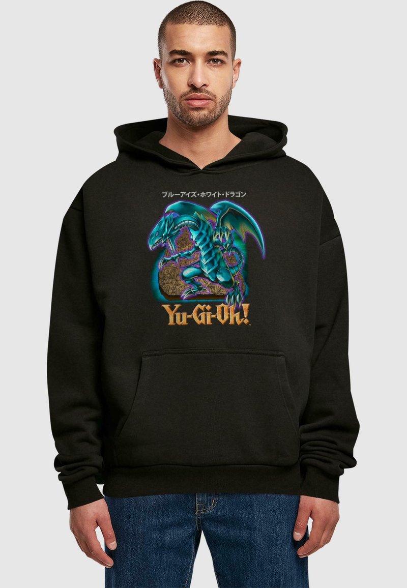 Sudadera negra con un diseño gráfico de un dragón azul sobre un globo dorado con el texto "Yu-Gi-Oh!". El material parece suave y tiene un bolsillo frontal.