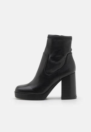 Black leather ankle boots with a high block heel, featuring a smooth finish, rounded toe, and elastic side panel for easy wear.