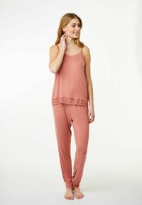 Dvoudílná souprava domácího oblečení v jemné dusty rose. Top na ramínka s krajkovým lemem, volné kalhoty se zúženými manžetami. Hladká textura, uvolněný design.