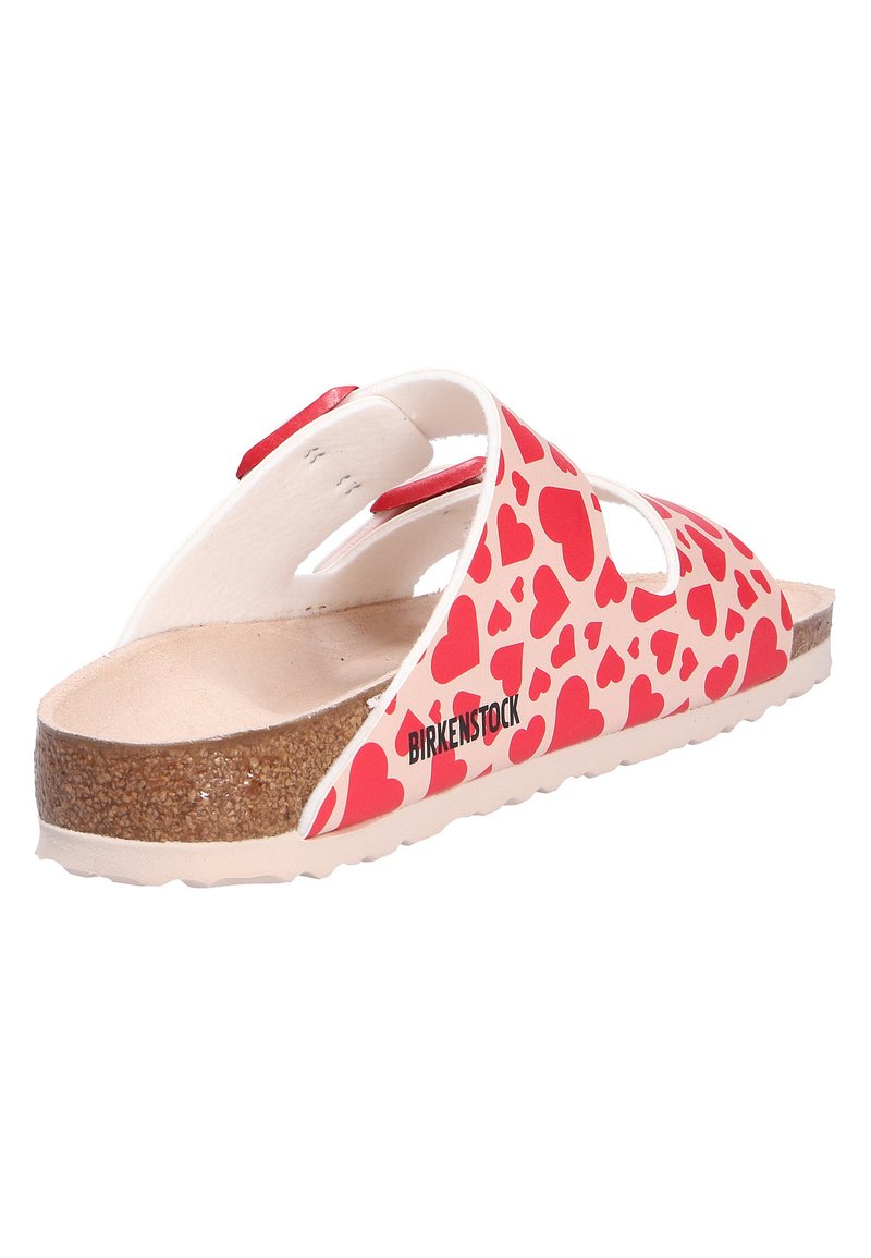 Sandalo Birkenstock con suola in sughero, cinture bianche decorate con cuori rossi e due fibbie regolabili rosse.