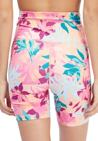 Pantaloni sportivi a vita alta, multi-colorati, con un motivo floreale tropicale in rosa, viola e verde acqua su uno sfondo pesca.