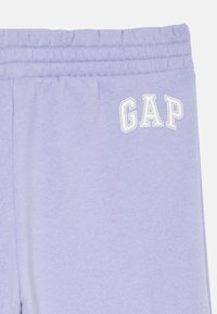 Lila elastični hlače za sweatpants s belim logotipom "GAP" na zgornjem levem stegnu.