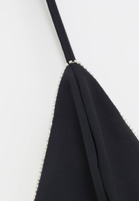 Bolsa de tela negra con un diseño triangular, adornada con un ribete de cuentas plateadas en el borde y una correa ajustable y elegante.