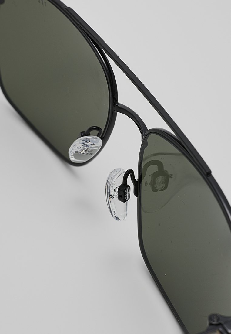 Schwarze Metall-Sonnenbrille mit dunkelgrünen Gläsern, ausgestattet mit verstellbaren klaren Nasenpads und einem minimalistischen Rahmen-Design.