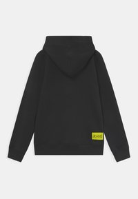 Felpa nera con cappuccio, dal tessuto liscio e con polsini a costine. Presenta un'etichetta verde brillante con la scritta "JEANS" in basso a sinistra.