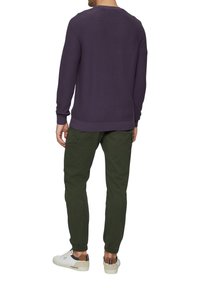 Paarse gebreide trui met geribbelde manchetten, gecombineerd met groene cargo-broek en witte sneakers. Kenmerken zijn onder andere een strakke enkel en zijzakken.