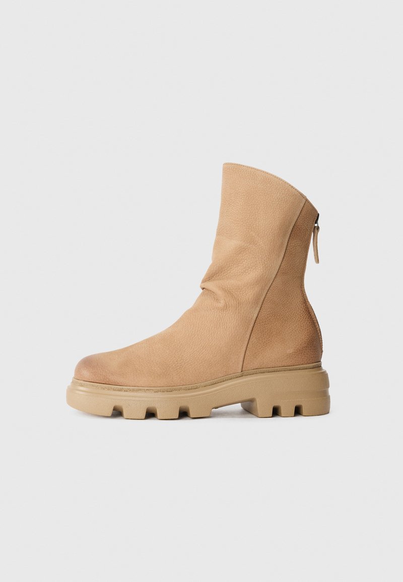 Bottines beiges en cuir texturé, présentant un bout lisse, une fermeture éclair sur le côté et une semelle en caoutchouc épaisse avec un motif de crampons distinct.