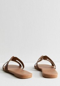 Bruine platte sandalen met een minimalistisch ontwerp, voorzien van kruisriemen en uitsnijdingen. Gladde textuur en een flexibele zool.