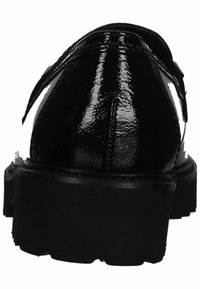 Zapatos de charol negro con una suela gruesa, que presentan una textura suave y una forma redondeada. Se puede ver un detalle de correa lateral.
