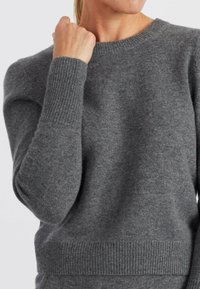 Maglione grigio realizzato in morbido tessuto a maglia testurizzata. Presenta un collo a giro, polsini e orlo a costine, con una leggera sagomatura alle spalle.