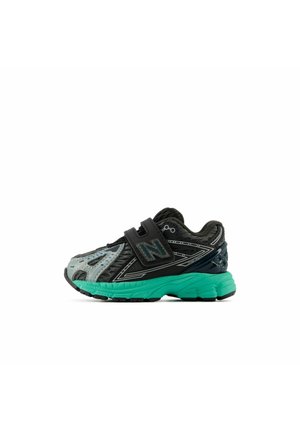 Black and gray New Balance sneaker with teal sole and single black Velcro strap, designed for children.