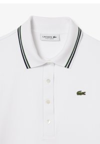Polo bianca a vestibilità slim, con colletto a righe verdi e blu navy e logo di coccodrillo ricamato in verde sul petto.