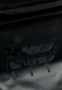 Svart tygväska inuti med dragkedja, med en mjuk läderflik och flera tygfickor med vertikal sömnad.