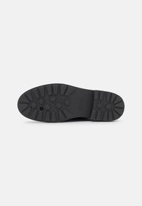 Schwarze Gummisohle mit strukturiertem Profil, das mehrere sternförmige Muster und Rillen für einen guten Halt aufweist, beschriftet mit "Clarks".