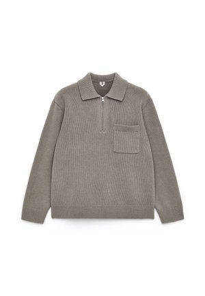 Sweater in muted beige, made of textured knit material, featuring a collar, half-zip front, and a small chest pocket.