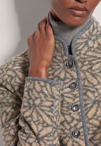 Beige wollen jas met grijze accenten, met een gestructureerd bladdesign, ronde knopen en een hoge kraag.
