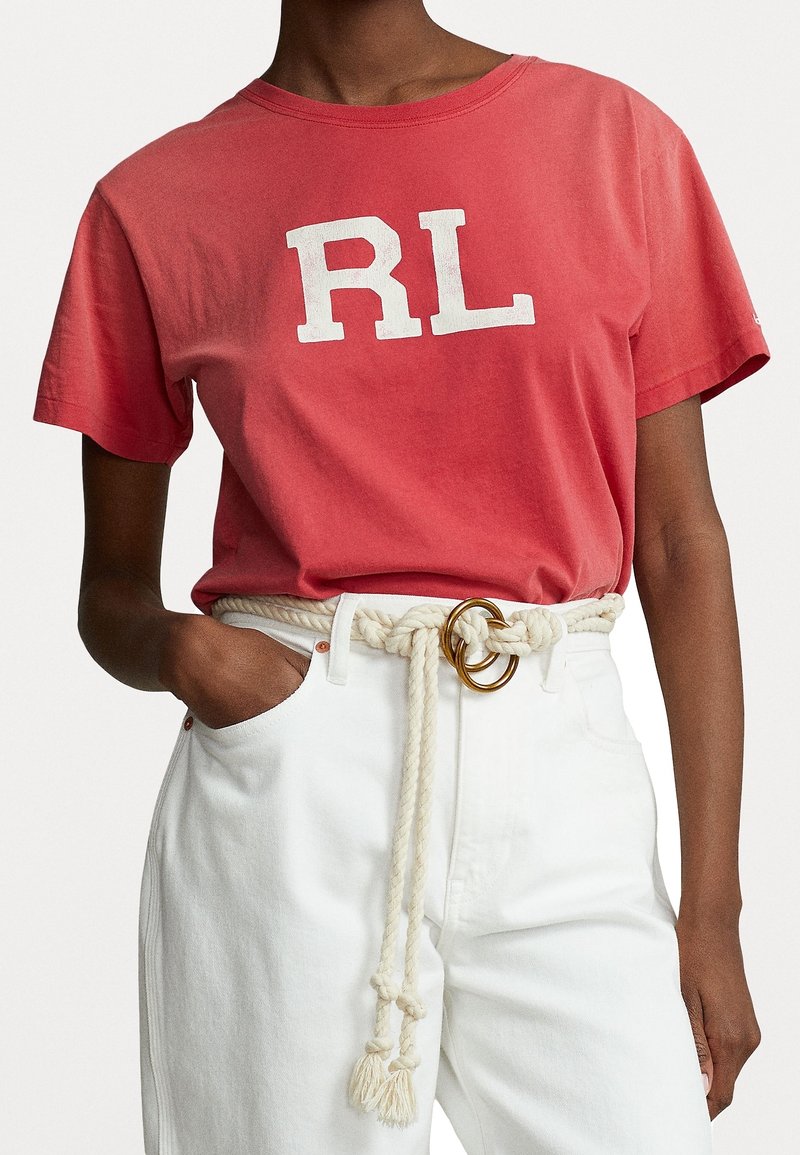 Röd bomulls-t-shirt med vit "RL" logotyp, korta ärmar. Matchad med vita denimbyxor och ett knutet repbälte med metallaccenter.