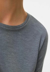 Maglietta grigia a maniche lunghe con scollatura rotonda, realizzata in materiale morbido e leggero che presenta una superficie liscia e leggermente testurizzata.