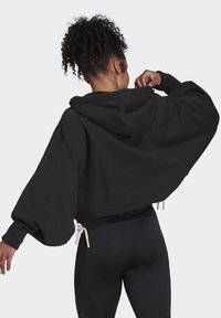 Felpa nera oversize con chiusura a coulisse sull'orlo, caratterizzata da maniche a palloncino e un cappuccio ampio per un comfort maggiore.