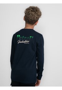 T-shirt à manches longues bleu marine avec un col arrondi, doté d'un logo graphique vert et blanc au dos, fabriqué à partir d'un tissu doux.