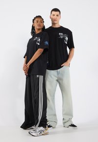 Black graphic t-shirts with blue accents, paired with black athletic pants featuring white stripes and light blue jeans. Sneakers with silver accents.