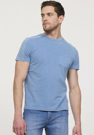 T-shirt bleu clair à manches courtes avec un col rond et une poche poitrine, fabriqué en coton doux, associé à un jean en denim.
