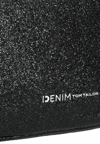 Zwart textuurmateriaal met een glanzende afwerking, voorzien van de "DENIM TOM TAILOR" branding in het wit. Het ontwerp richt zich op een slanke, minimalistische uitstraling.