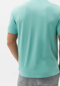 T-shirt turchese a maniche corte realizzato in tessuto morbido, con scollo rotondo e una texture liscia, dalla vestibilità regolare.