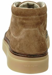 Braune Wildleder-Ankle-Boots mit abgerundeter Spitze, cremefarbener Gummisohle und Nähten. Die Rückansicht zeigt die weiche Textur und das Logo.