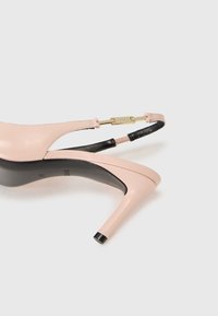 Scarpa con tacco alto in pelle rosa con un accento nero sul retro e una fibbia in metallo dorato, caratterizzata da un design elegante e curvo con punta affilata.