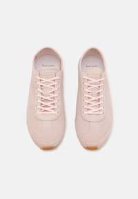 Vaaleanpunaiset mokkanahkaiset tennarit, joissa on teksturoitu yksityiskohtia, tasaiset nauhat ja kiinteä kumipohja. Sisäosassa on kultainen merkintä.