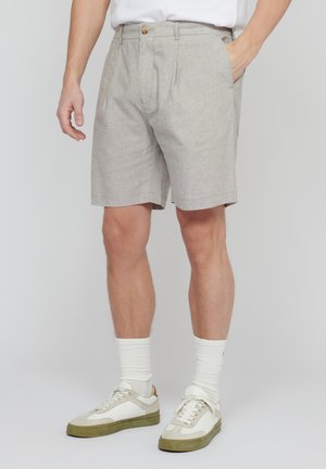 Lys grå shorts lavet af struktureret stof, med knaplukning og sidelommer, parret med hvide sokker og afslappede sneakers.