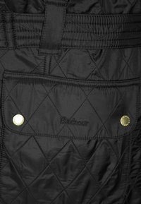 Casaco preto acolchoado com um bolso de fecho de botão, logótipo bordado "Barbour" e um padrão discreto de losangos em todo o tecido.