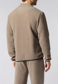 Pullover in pile marrone con colletto alto, polsini a coste e bordo nero all'orlo. Tessuto morbido e vestibilità comoda.