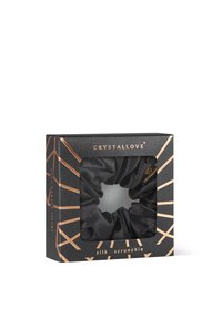 Czarna jedwabna gumka do włosów umieszczona w kwadratowym pudełku z przezroczystym okienkiem. Pudełko ma geometryczny złoty wzór oraz nazwę marki "CRYSTALLOVE."