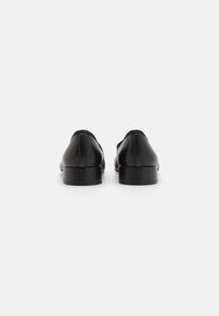 Black leather shoes with a low heel, rounded shape, smooth texture, and minimal stitching detail, viewed from the back.
