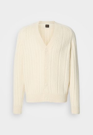 Krémszínű kötött kardigán v-nyakkivágással, függőleges bordázott textúrával és öt gombbal az elején. Puha anyag; hosszú ujjú.