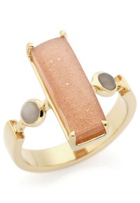 Goldring mit einem rechteckigen pfirsichfarbenen Stein, flankiert von zwei kleineren grauen Steinen; glatte Textur und polierte Oberfläche.