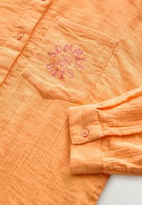 Oranges Hemd aus strukturiertem Stoff. Verfügt über eine Brusttasche mit dem Grafikmotiv "SUMMER DAYS" und detailreichen Knopfmanschetten.