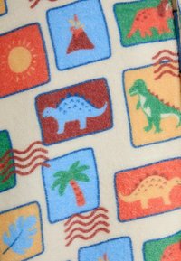 Plišana deka s veselih otiscima dinosaura i prirode unutar kvadrata, na krem pozadini. Meko tekstura s razigranim dizajnom.