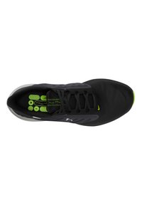 Zapatilla deportiva negra con acentos verdes, parte superior de malla, puntera redonda y cordones planos. Presenta una suela texturizada y un logotipo de marca prominente.