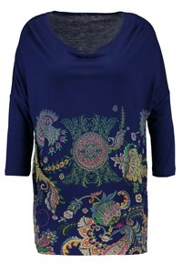 Haut bleu marine avec un col large et des manches trois-quarts, présentant des motifs floraux et paisley colorés sur le devant. Texture de tissu douce.