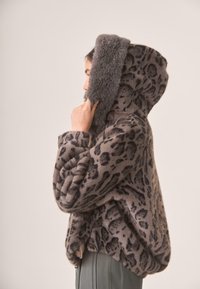 Chaqueta con capucha de estampado de leopardo, hecha de un material suave y peludo. Cuenta con una capucha de pelaje sintético gris esponjoso y mangas anchas.