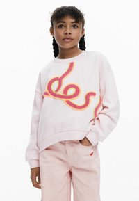 Felpa rosa chiaro con un design ricamato colorato e testurizzato. Vestibilità morbida con polsini e orlo a coste, abbinata a pantaloni rosa chiaro.