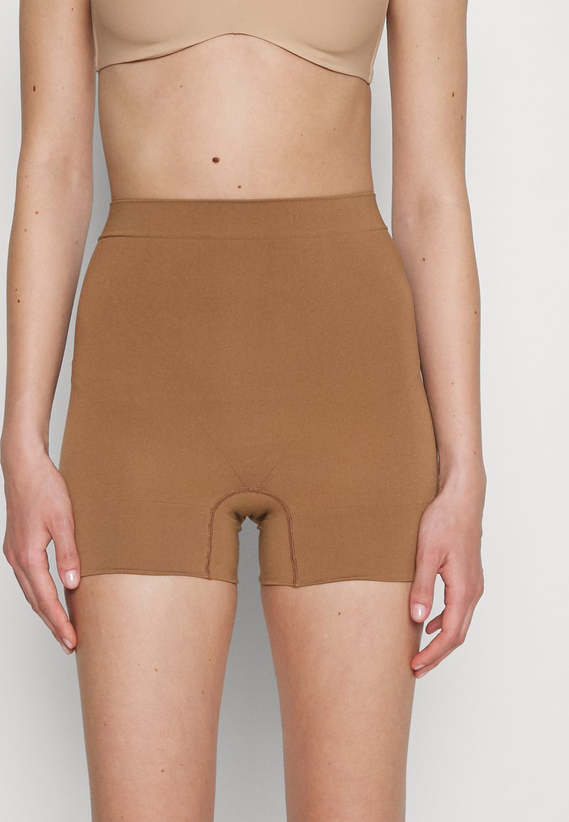 Bruine shapewear shorts met een gladde textuur, hoge tailleband en een snit tot halverwege de dij. Bevat versterkte stiksels en een ingebouwde slip-ontwerp.