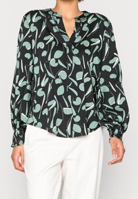 Blusa nera con stampa botanica verde, maniche lunghe a sbuffo e scollatura a V con chiusura a bottone. Tessuto dalla superficie liscia.