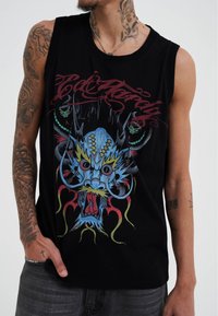 Czarny top na ramiączkach z kolorową grafiką smoka o skomplikowanych detalach, otoczony stylizowanym tekstem i akcentami w kolorach czerwonym, niebieskim i zielonym.