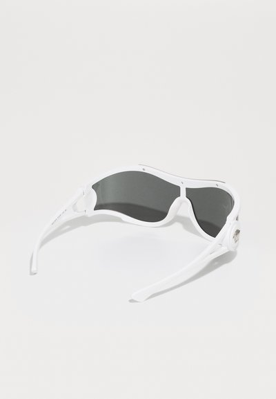 White sunglasses with dark lenses. Sleek, wrap-around design. Plastic frame with accent hardware on the side. Curved, smooth texture.