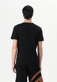 Sort bomulds T-shirt med klassisk rund hals og korte ærmer, der har en glat tekstur og et enkelt, rent design.
